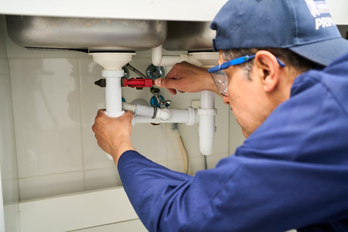 Plumber repairing the pipework under a kitchen sink